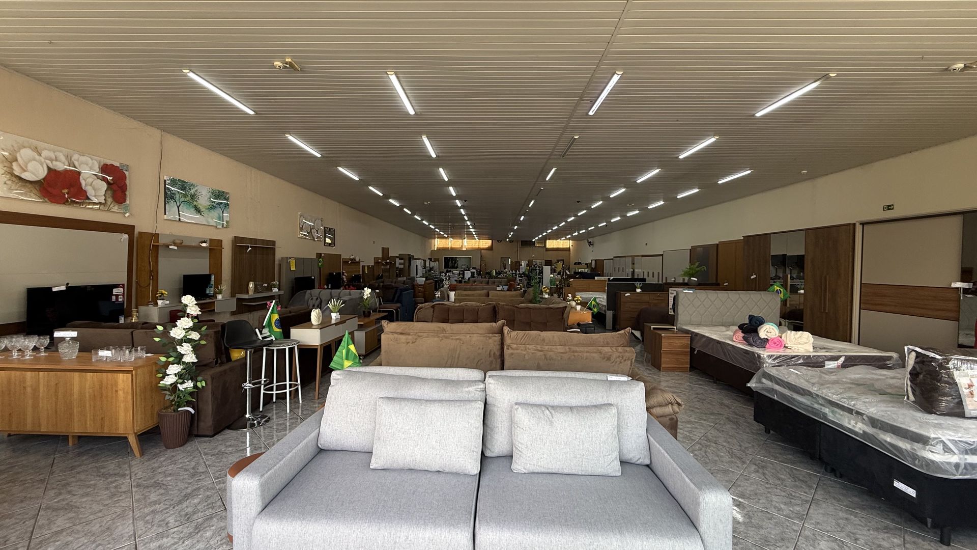 Salão da loja Ideal de Ribeirão Bonito com sofá cinza, camas box e móveis de sala