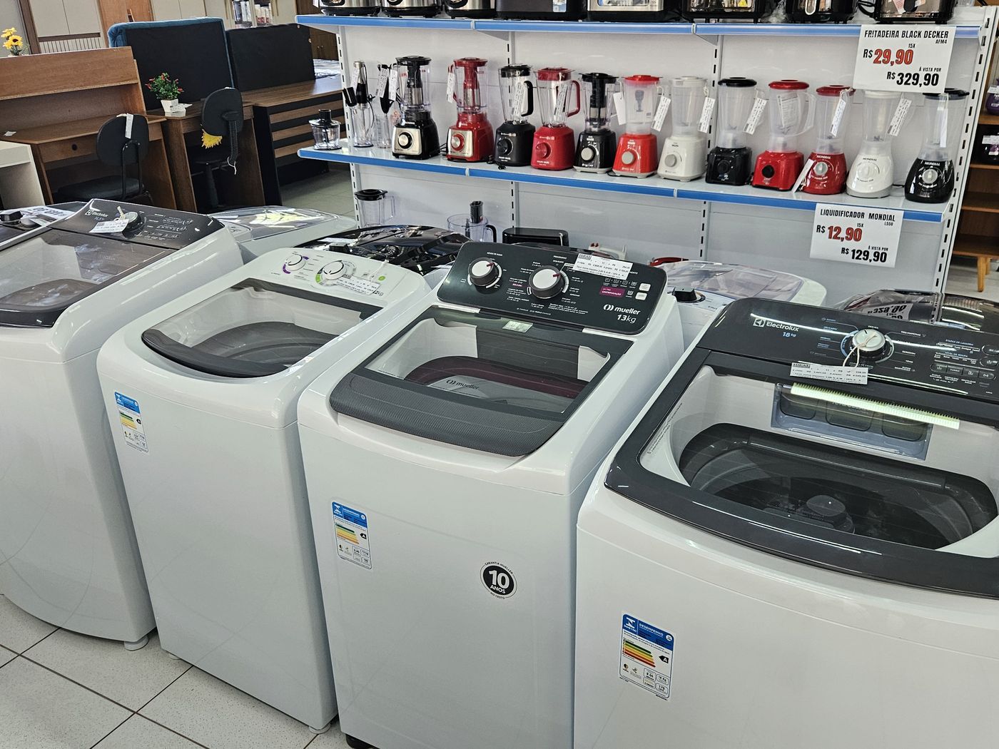 Máquinas de lavar roupa enfileiradas e prateleira de liquidificadores